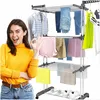 A woman is posing next to a three-tier clothes drying rack filled with various garments. The rack is mobile and appears to be made of metal and plastic. Shoes are visible on the bottom shelf of the rack. Náhľad obrázku produktu