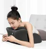 A woman is lying on a bed, using a pillow and her phone. Produktbild-Vorschau