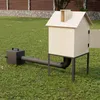 A wooden smoking house with a connected pipe and a black firebox sits on a grassy lawn. Náhľad obrázku produktu