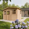 A wooden garden shed is shown in a backyard setting, with a modern house in the background and flowers in the foreground. Náhled obrázku produktu