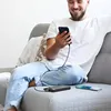 A man is sitting on a couch, holding a smartphone that is connected to a power bank. Anteprima dell’immagine prodotto