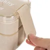 A close-up shot of a beige lunchbox with a hand opening the latch. Podgląd zdjęcia produktu