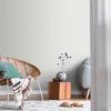 A cozy living room scene with a wicker chair, a small wooden side table with a vase and decorative branches, and a glimpse of a sofa. Produktbild-Vorschau