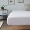 A close-up view of a white fitted sheet on a bed. Náhľad obrázku produktu