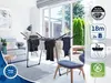 A drying rack with clothes is set up in a living room with a large window overlooking a garden. Produktbild-Vorschau