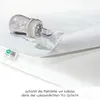 A baby bottle is shown lying on its side, spilling liquid onto a white mattress protector. The protector is partially lifted to reveal its texture and a label. Produktbild-Vorschau