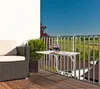 A balcony with a chair, table, and pitcher of drinks, overlooking a rural landscape. Náhled obrázku produktu