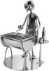 A metal figurine of a person grilling fish on a barbecue. Produktbild-Vorschau
