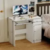 A white computer desk with a monitor, keyboard, and books on it, placed next to a bed. Podgląd zdjęcia produktu