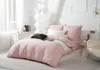 A bedroom scene with a pink duvet cover on a bed, decorated with pillows and a throw blanket. Podgląd zdjęcia produktu