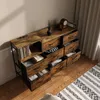 A dresser with multiple drawers and a shelf unit on the left, all in a vintage wood finish, placed on a wooden floor next to a rug. Náhľad obrázku produktu
