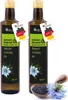 Two bottles of black cumin oil are displayed side-by-side, with a small wooden bowl of black cumin seeds and a blue flower in the foreground. Produktbild-Vorschau