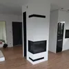A modern living room with a white corner fireplace and a black insert. Produktbild-Vorschau