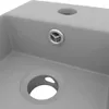 A close-up view of a gray ceramic sink with two holes and a drain. Produktbild-Vorschau