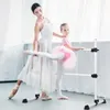 A ballet instructor is assisting a young student at a ballet barre in a studio. Náhled obrázku produktu