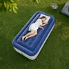 A woman sleeping on an inflatable mattress on the grass, with a tent and camping chairs in the background. Anteprima dell’immagine prodotto
