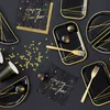A collection of New Year's Eve party supplies, including plates, napkins, cups, and decorative stars, arranged on a black surface. Produktbild-Vorschau
