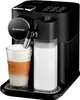 A black Nespresso coffee machine with a glass of latte and a milk carafe. Produktbild-Vorschau