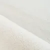 A close-up view of a fluffy, white rug. Anteprima dell’immagine prodotto