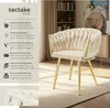 A cream-colored armchair with gold legs is shown in a room with a bookshelf and a cabinet. Produktbild-Vorschau