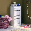 A white storage unit with four drawers is shown in a room with olive green walls and a patterned rug on the floor. A colorful woven basket filled with clothes is next to the unit, and a string of colorful paper circles hangs on the wall. Anteprima dell’immagine prodotto