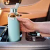 A hand placing a water bottle into a car's cup holder. Anteprima dell’immagine prodotto