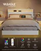 A modern white bed frame with LED lighting and integrated charging stations, displayed in a bedroom setting with bedside tables and lamps. Produktbild-Vorschau