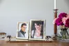 Two framed photos on a tray with flowers and a candle holder. Produktbild-Vorschau