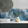 A bathroom vanity with a sink, faucet, and decorative items, featuring a marble-patterned backsplash. Podgląd zdjęcia produktu