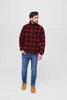 A man wearing a red and black plaid jacket and blue jeans, standing against a white background. Produktbild-Vorschau