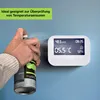 A hand sprays a can of cold spray towards a digital device mounted on a blue wall. Produktbild-Vorschau