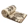 A rolled-up blanket with a floral pattern on a white background. Produktbild-Vorschau