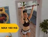 A woman is doing pull-ups on a pull-up bar mounted in a doorway, reflected in a mirror. There is also a poster on the wall and a plant in the background. Voir les images du produit