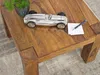 A close-up of a wooden coffee table with a decorative metal car and a pen on a notepad. Produktbild-Vorschau