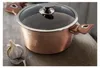 A rose gold pot with a glass lid sits on a wooden surface next to a head of garlic. Podgląd zdjęcia produktu