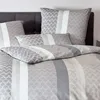 A neatly made bed with patterned bedding. Produktbild-Vorschau