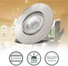 A close-up of a recessed LED spotlight with a brushed metal finish, set against a blurred background of a modern interior with other spotlights visible on the ceiling. Three circular icons with feature descriptions are displayed below the spotlight. Produktbild-Vorschau