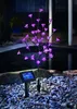 A solar-powered LED flower bush with pink lights sits in a garden setting at night, next to a pond. Produktbild-Vorschau
