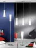 A collection of modern floor and pendant lamps with glass shades and chrome bases, displayed in a room setting with blue and gray walls. Voir les images du produit