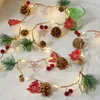 A Christmas garland with lights, pinecones, red berries, and wooden cutouts of stars and trees. Produktbild-Vorschau