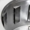 A close-up view of the interior of a metal object with several angled blades or fins. Náhled obrázku produktu