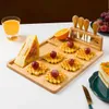 A breakfast or snack spread on a wooden board, featuring waffles, a sandwich, fruit, and a glass of juice. Náhľad obrázku produktu