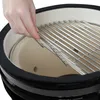 A hand is placing a grill grate into a ceramic kamado grill. Produktbild-Vorschau