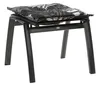 A black ottoman with a patterned cushion on top, isolated on a white background. Produktbild-Vorschau