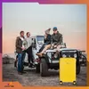 Four people are posing with a yellow suitcase next to a white off-road vehicle on a dirt road with a scenic sunset in the background. Anteprima dell’immagine prodotto