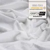 A close-up of white, textured fabric, likely a bedsheet or towel, with a product certification label in the upper right corner. Produktbild-Vorschau