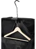 A black garment bag with a wooden hanger inside, suspended by a metal hook. Anteprima dell’immagine prodotto