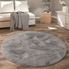 A round gray rug is placed on a wooden floor in a living room setting, with a sofa and a side table visible in the background. Anteprima dell’immagine prodotto