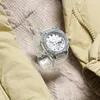 A clear G-Shock watch is placed on a textured beige fabric, with a light yellow jacket partially visible on the sides. Voir les images du produit