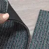 A close-up of carpet tiles, showing the texture and backing of one tile being lifted by a hand, with another tile lying flat. Produktbild-Vorschau